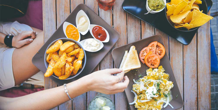 Womans-Hand-Taking-Food-From-Cafe-Table-With-Dips-And-Drinks