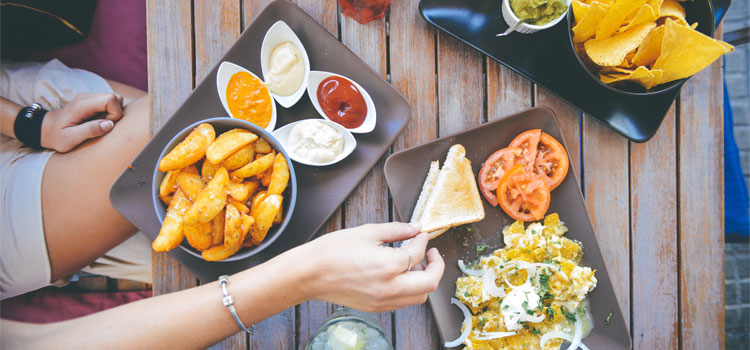 Womans-Hand-Taking-Food-From-Cafe-Table-With-Dips-And-Drinks